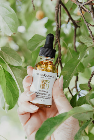 Hand holding a bottle of retinol eye repair oil with a natural background