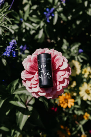 Black lip balm on a pink flower with a blurred floral background