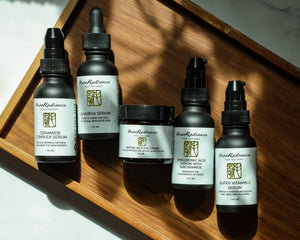 Set of skincare products on a wooden tray with natural light casting shadows.